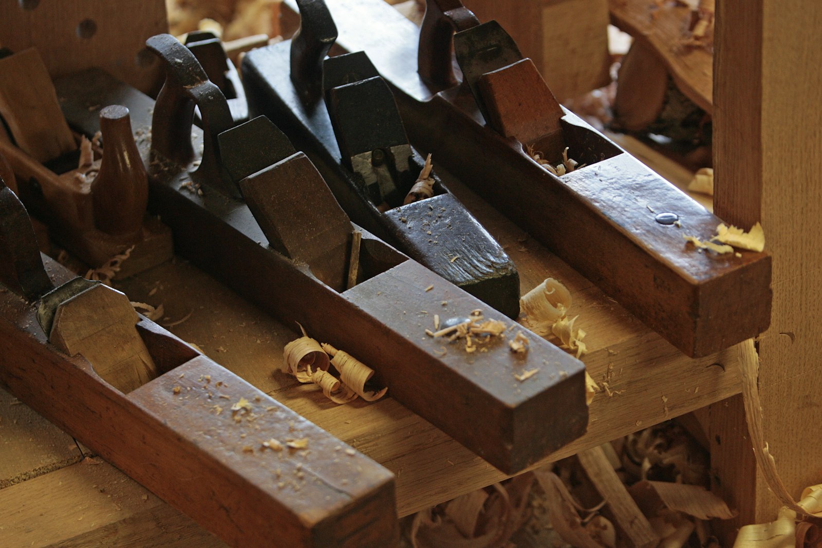 Wooden hand planes resting on a workbench with shavings